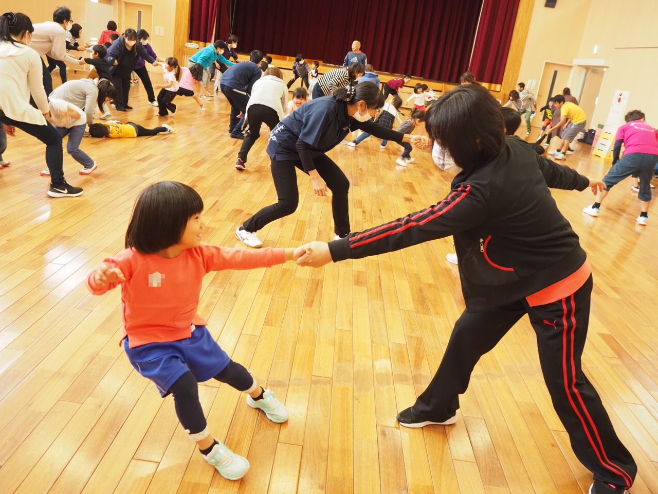 親子で手をつなぎ互いの尻をたたき合う運動遊び
