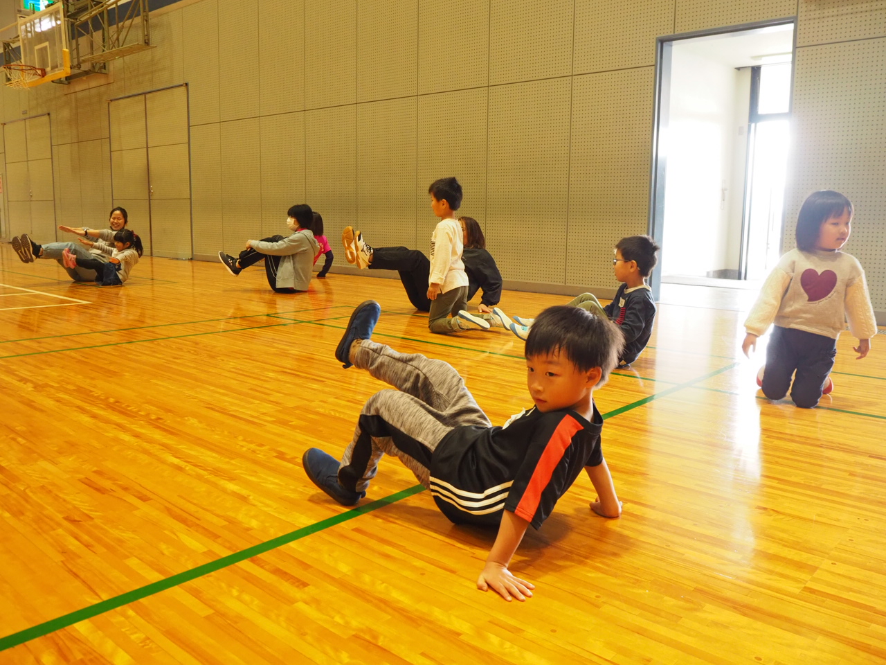 両足を上げるポーズをとる子ども