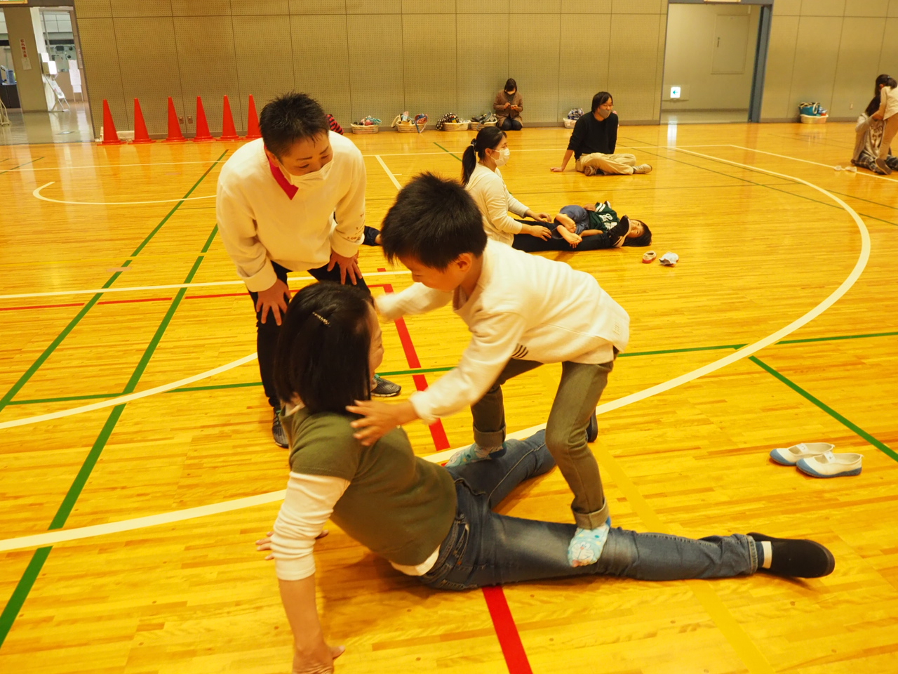 お母さんの太ももの上を歩く子どもとそれを見守るスタッフ