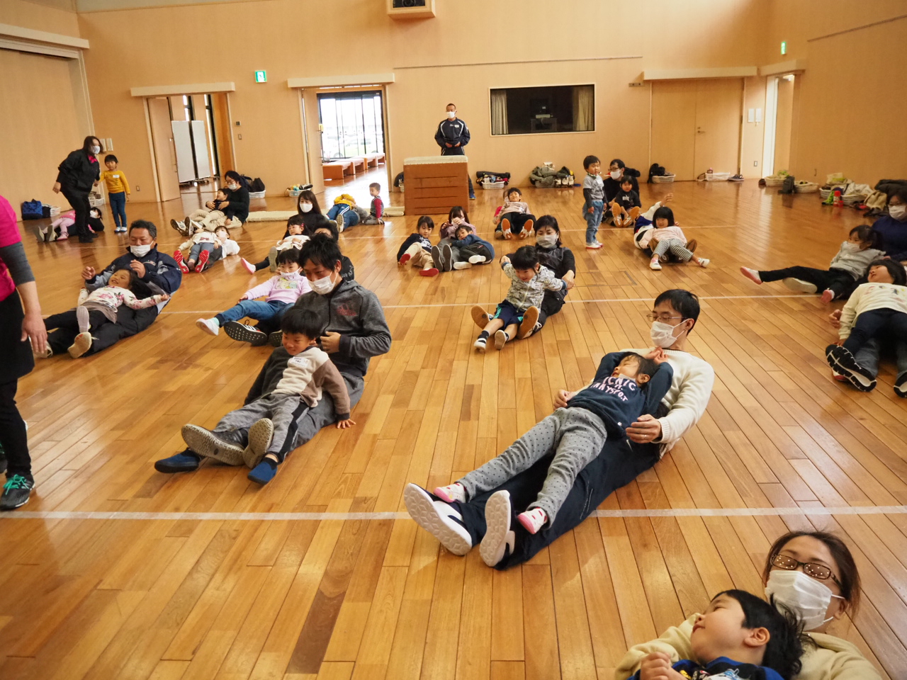 寝転がった親の上に寝そべる子どもたち