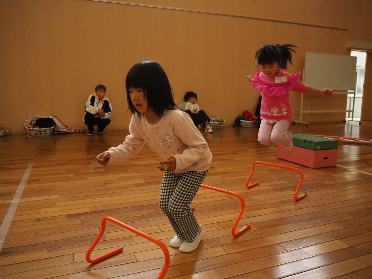 小さなハードルを跳ぶ子どもたち