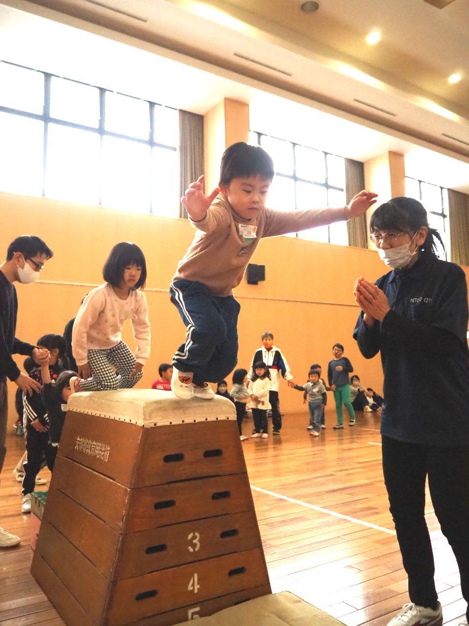跳び箱を跳ぶ子どもと見守るスタッフ