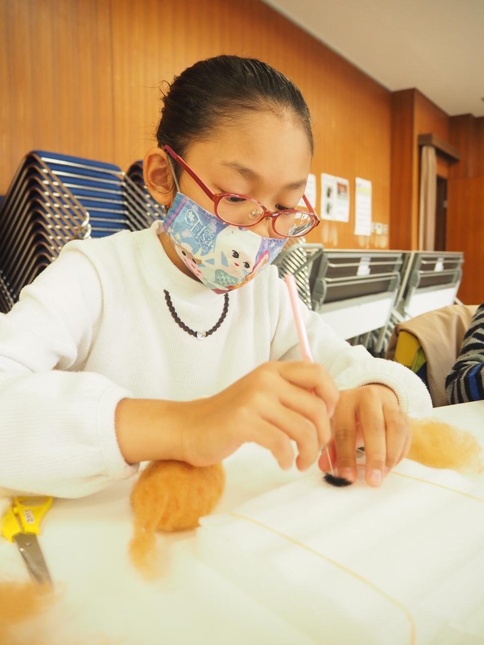 小さい耳の部品を針で刺す子ども