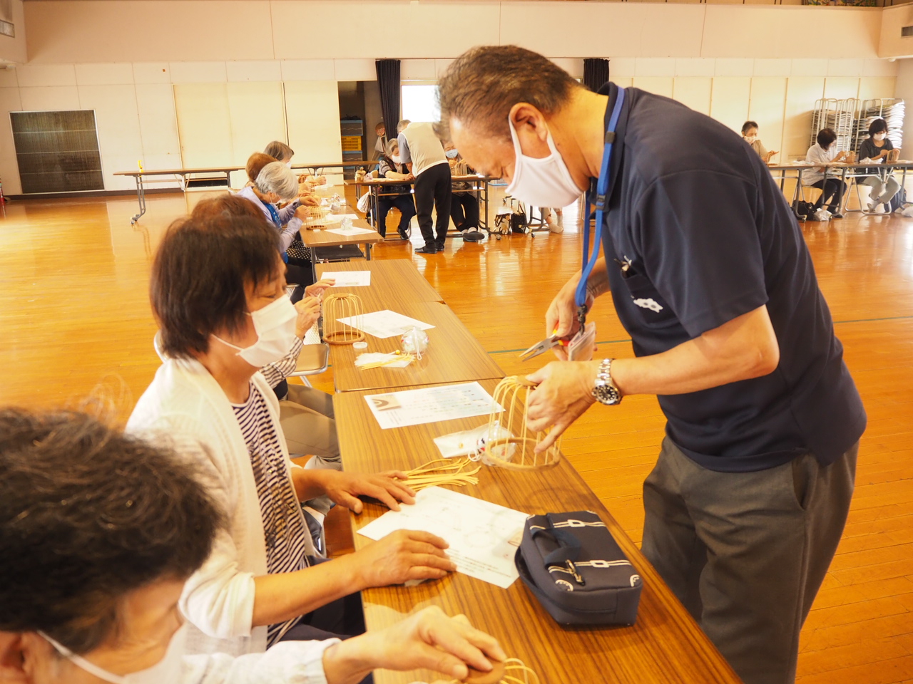 竹かごの修正を手伝う公民館スタッフ