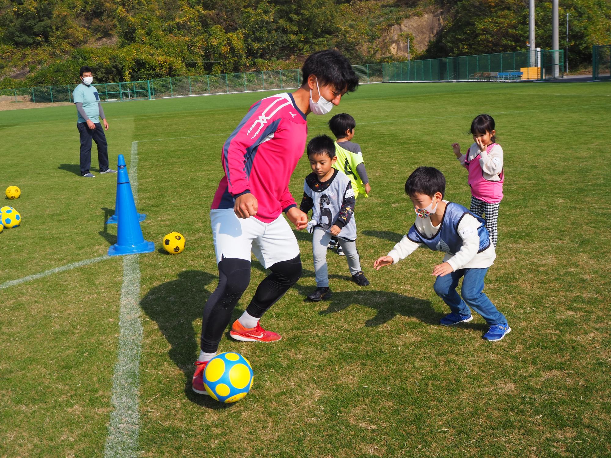 サッカーする学生と子ども