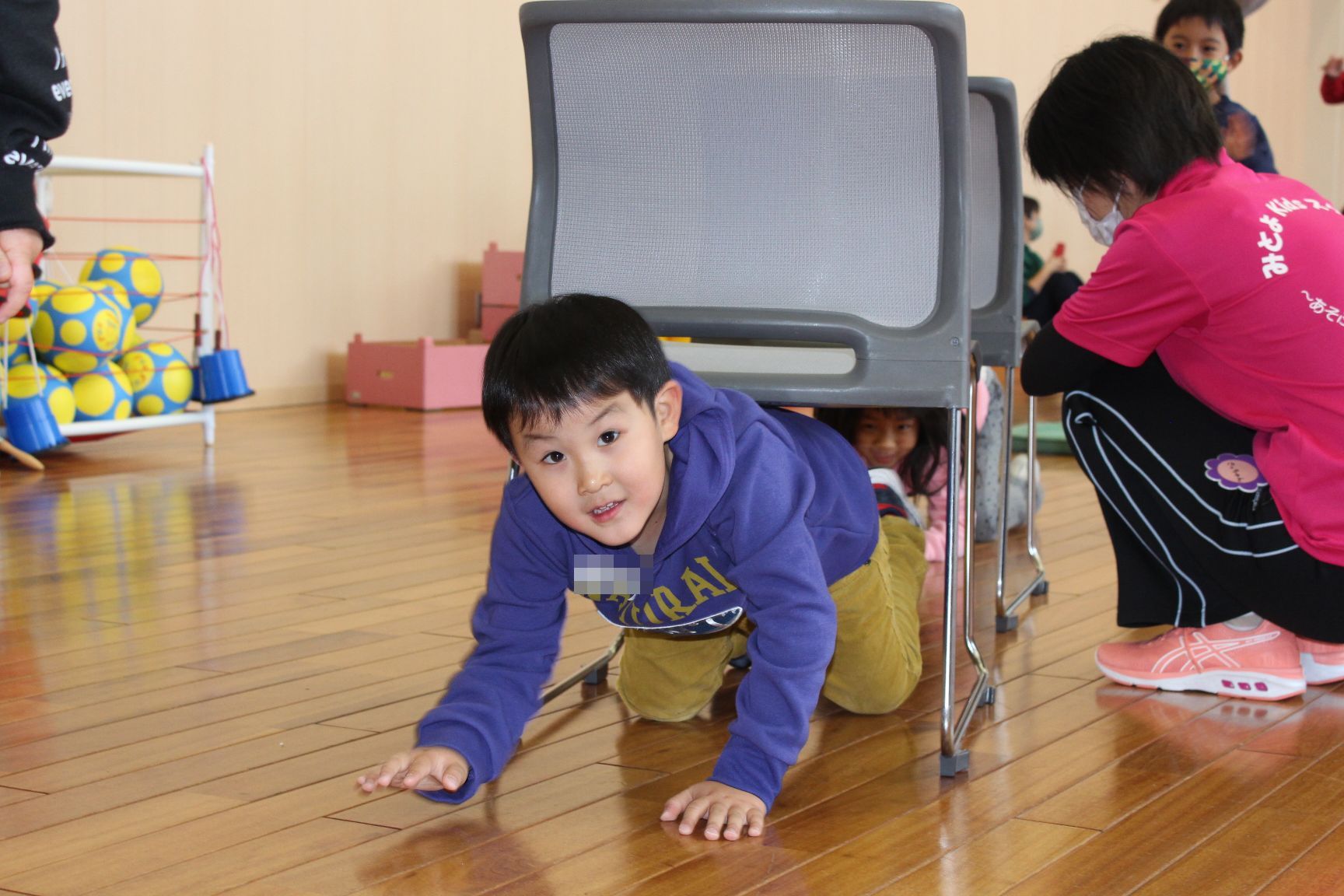 椅子のトンネルをくぐる子ども