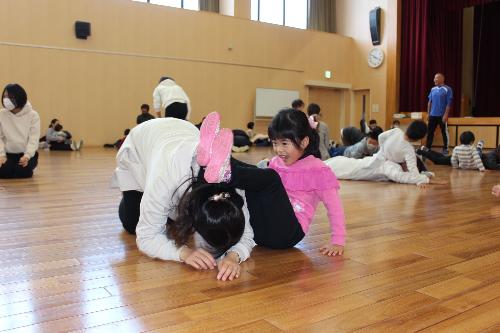 子どもの足のトンネルをくぐろうとする保護者