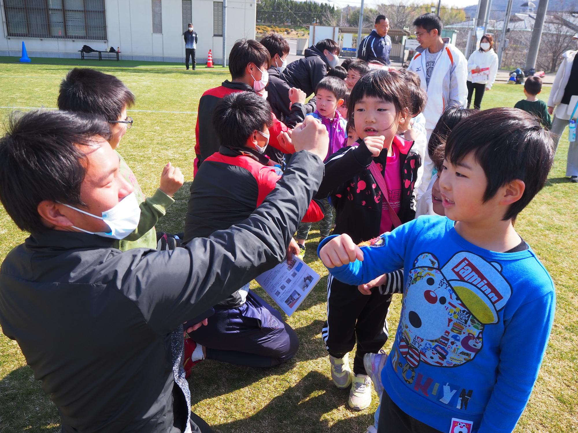 サッカー部のお兄さんと肘タッチする子どもたち