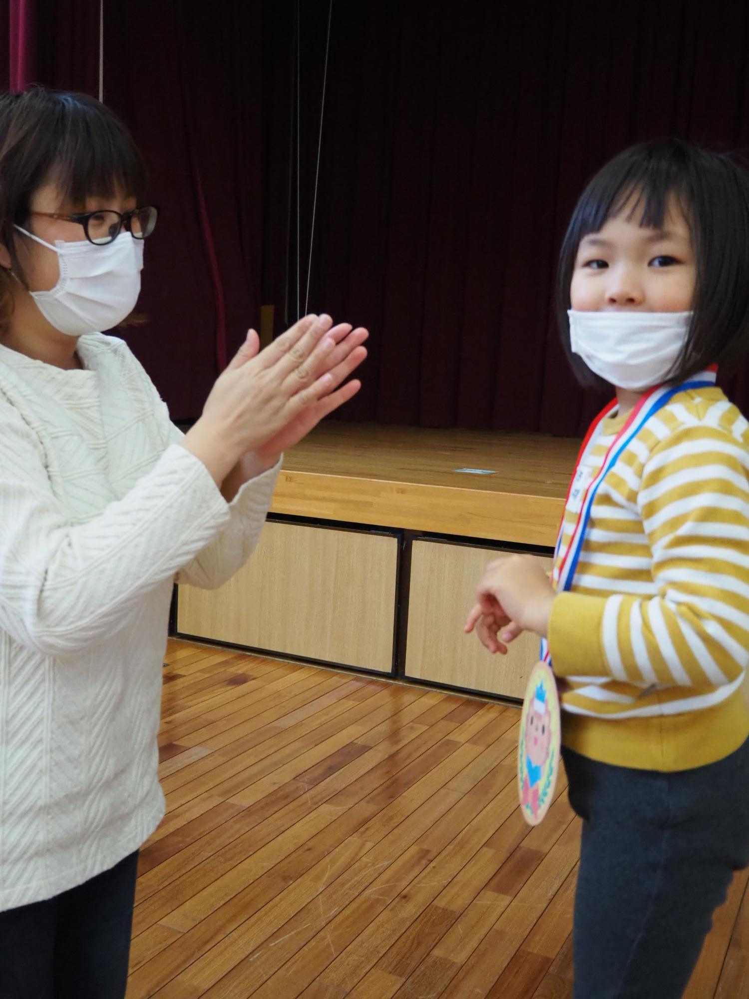 母親にメダルをかけてもらう子ども