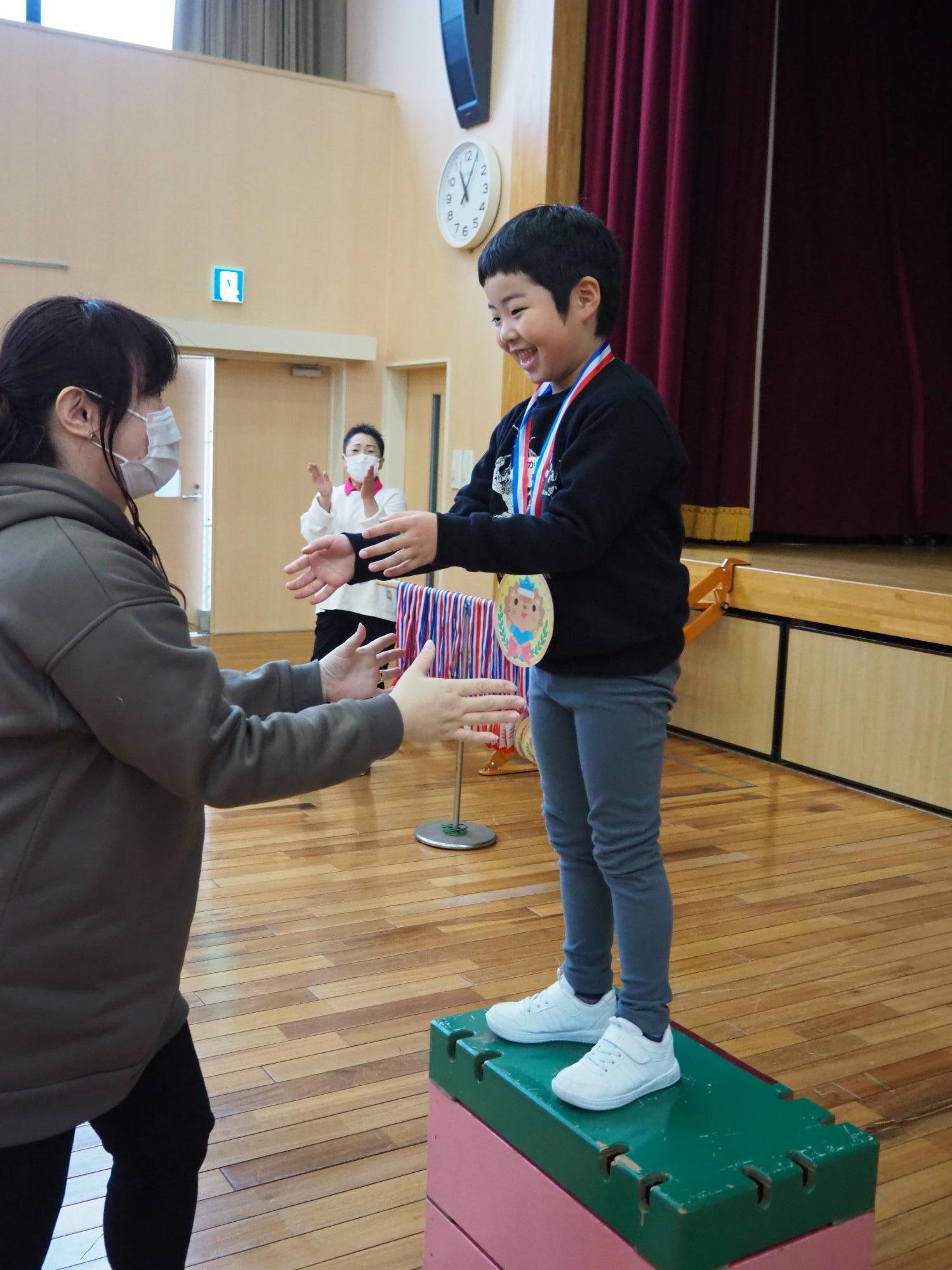 母親にメダルをかけてもらう子ども