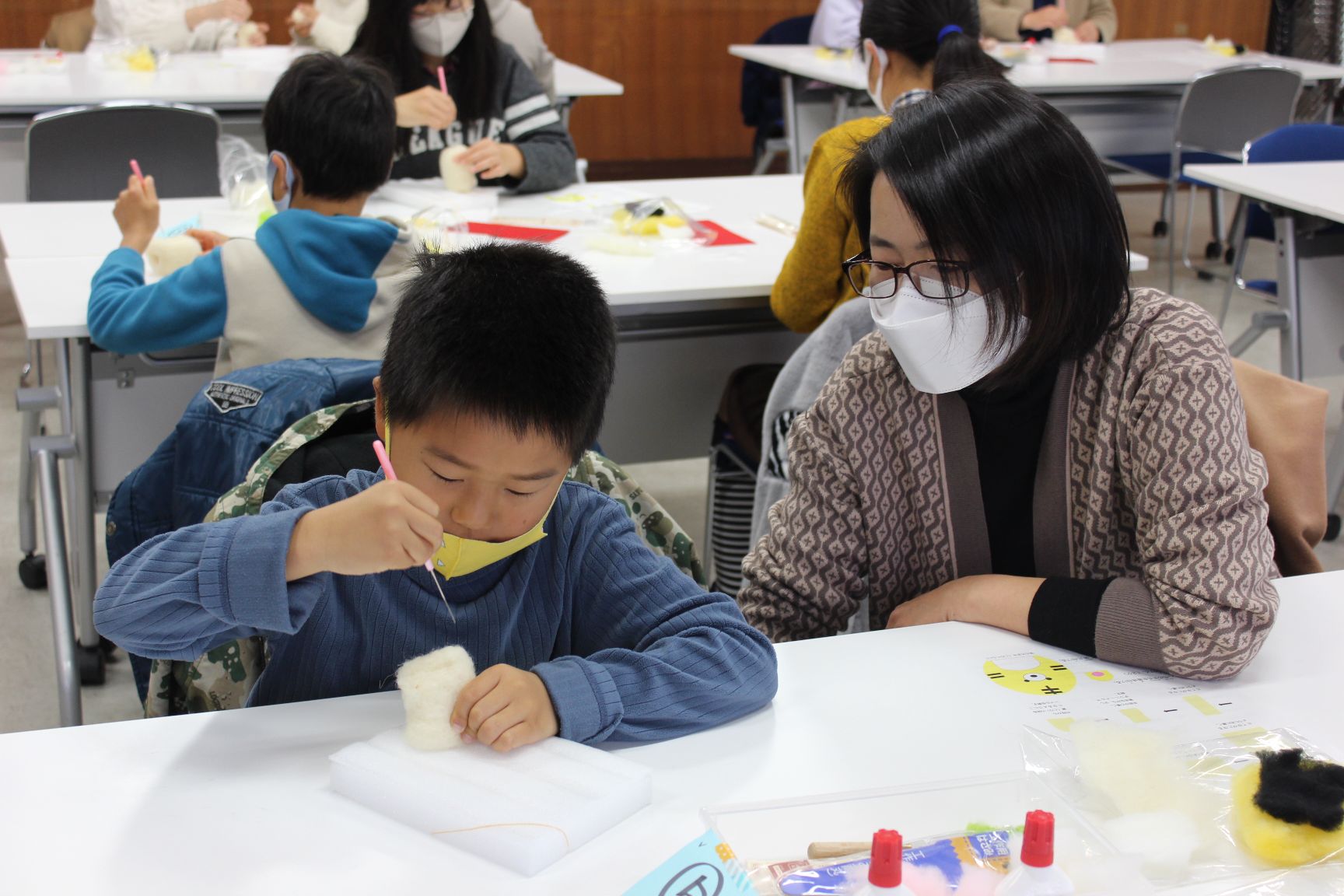 子どもの作業を見守る保護者