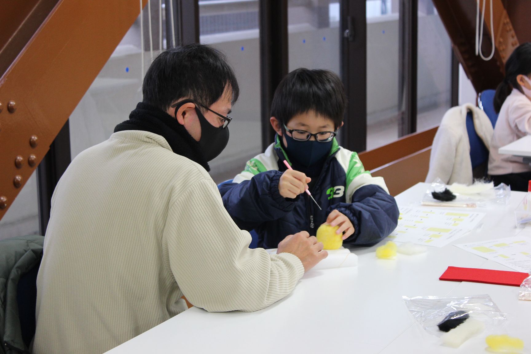 子どもの作業を手伝う保護者