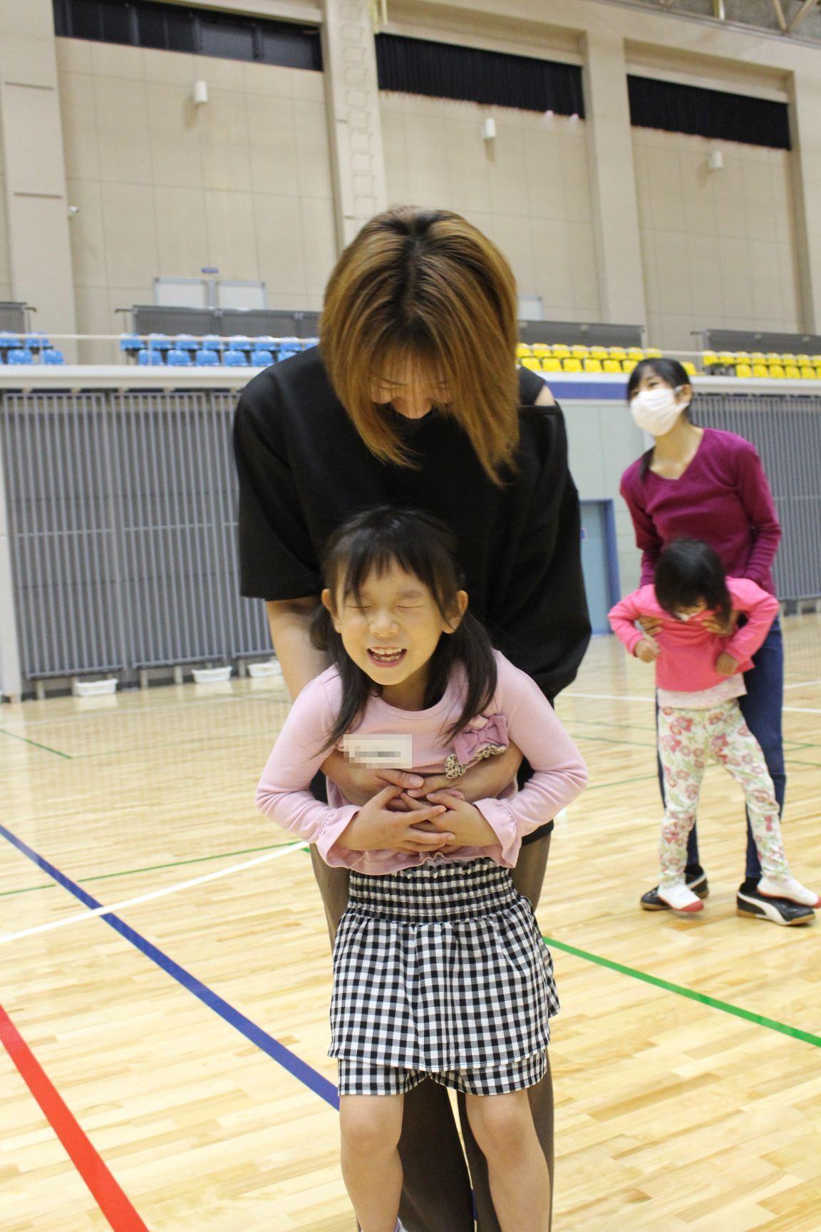 目を閉じて後ろからだっこされるこども