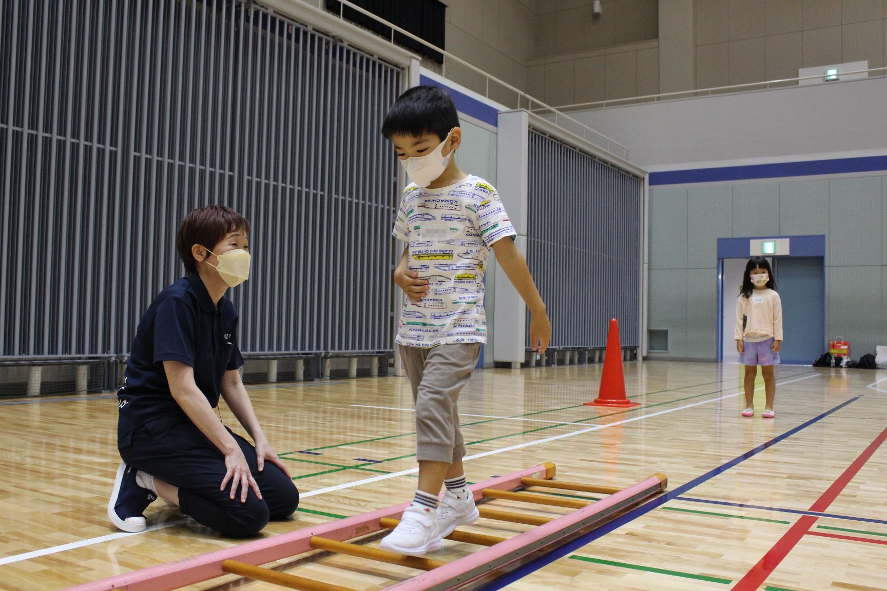 横に倒したはしごの上を歩く子ども