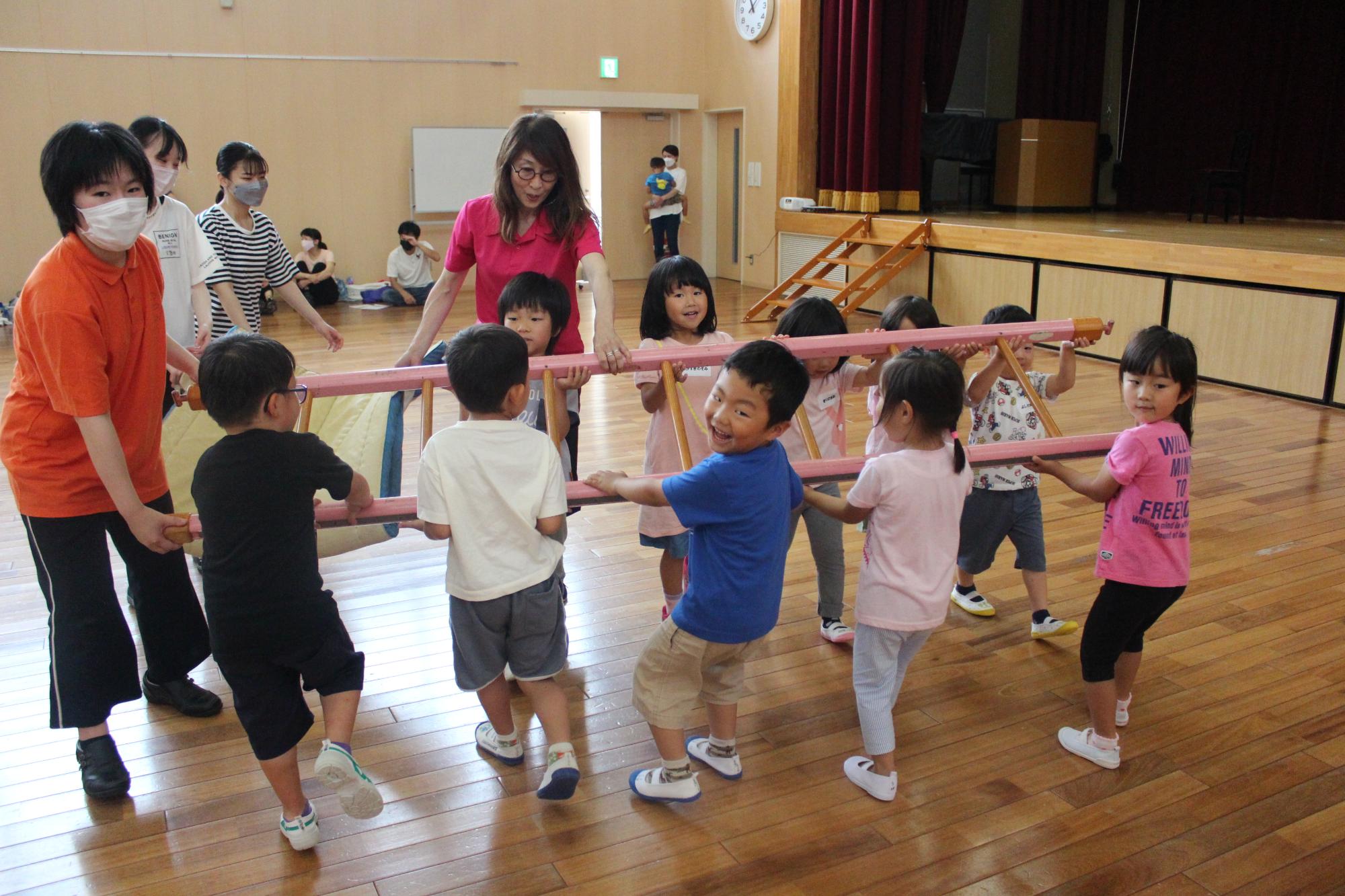 大人と一緒にはしごを片付ける子どもたち