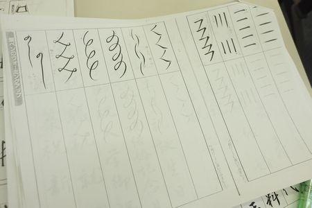 筆使いを練習するための「一」や「川」などの文字が書かれている紙が写っている写真