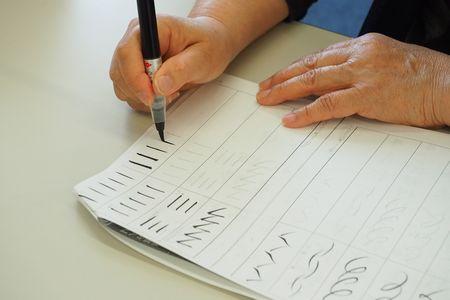 練習用の紙に筆ペンで「一」を書いている手元が写っている写真