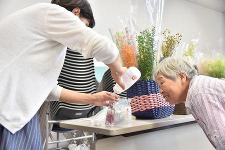 講師の高橋 美貴子さんが瓶にオイルを流し込んでいる様子を真剣な表情で見ている女性の受講生の写真