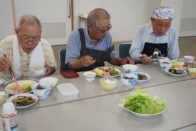 出来上がった料理を食べている3人の男性の写真