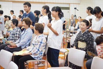 椅子に腰かけている来場者の後ろに立って肩たたきをしている生徒たちの写真