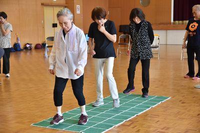 緑のマットの上に三人の女性参加者達が立っていて運動をしている写真