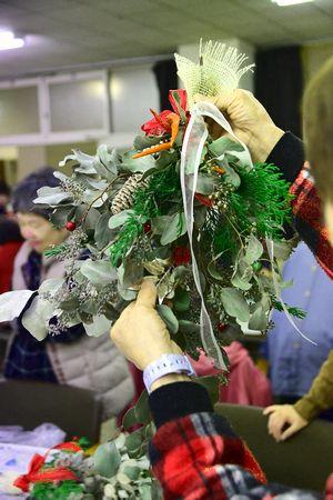 参加者が手にまつぼっくりやリボンがついたクリスマスリースを持っている写真