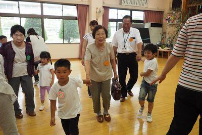 園児たちが高齢者の手を引いて歩いている写真