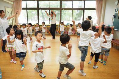 園児たちが円を作って高齢者の方と踊りながら歩いている写真