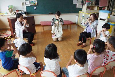 先生と高齢者の方と園児たちが円になって手遊びをしている写真