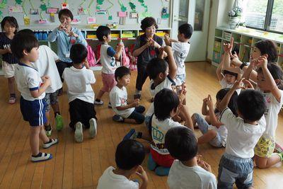 園児たちが高齢者の方に手遊びを教えている写真