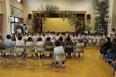 園児たちが整列して高齢者の皆さんに向かって歌を歌っている写真