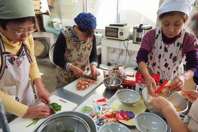 女性3人が材料を切ったり、インスタントラーメンの袋から麺を取り出している写真