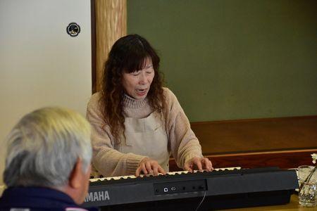 三崎 めぐみさんがキーボードを演奏しながら歌っている写真