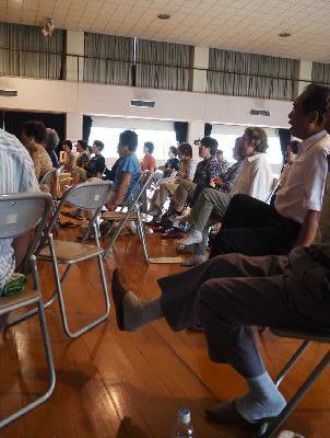 参加者達がパイプ椅子に座りながら片足を上にあげている写真
