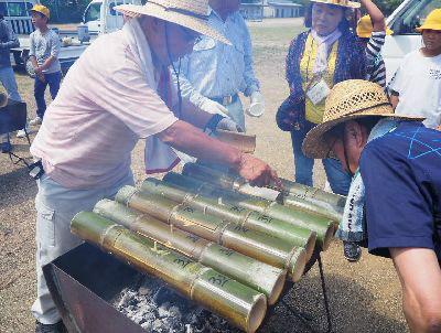 コンロからは煙が上がっていて、竹筒のお米の様子を年配の男性たちが見ている写真