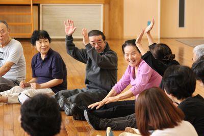 両手を挙げ座っている2人の参加者や笑顔で座っている参加者たちの写真