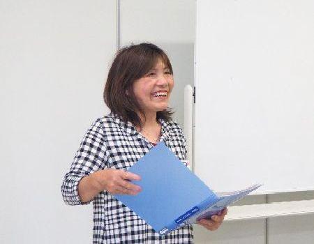 アシスタントの田原 任子先生が手に持った青いファイルを開きながら話をしている写真
