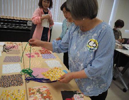 参加者が机の上に置かれた折り紙の柄とひもの色を選んでいる写真