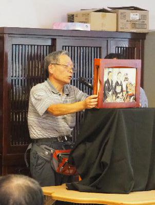 黒い布がかかっている台に手紙芝居を乗せて男性が読み聞かせをしている写真
