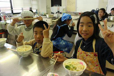 うどんを食べながらピースサインをしている子供たちの写真