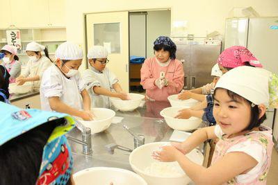 5人の子供たちがボールに入った小麦粉を練っている写真