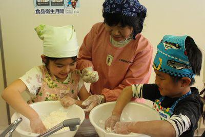 大西さんに教えてもらいながら嬉しそうに小麦粉を練っている2人の子供の写真