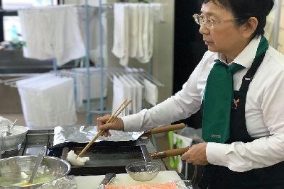 菜箸で挟んだ紙で卵焼き器に油を塗っている角田 眞理子先生の写真