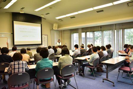 前面に大きなスクリーンがあり横に講師の道久 礼子さんが立って、参加者たちが座っている写真