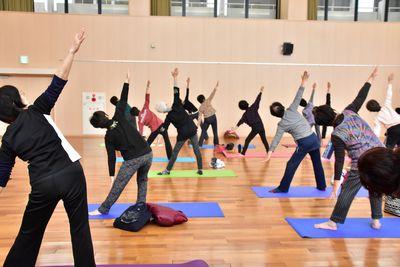 両足を広げて立ち両腕を肩の高さにあげ左に傾いたポーズをしている参加者たちの写真