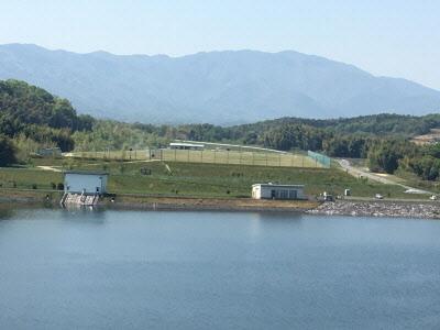 奥に山と芝生公園が広がる宝山湖の写真