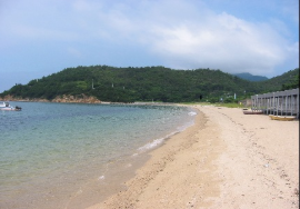 砂浜から島が見える海水浴場の写真