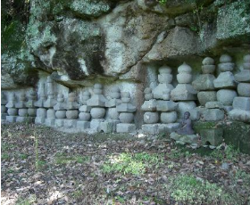 岩の下にある石塔群の写真