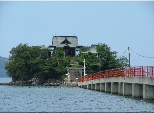 赤い渡り橋の先に見える小さな島に祀られている津嶋神社の写真