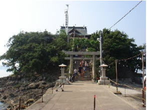 渡橋の先の島の中に祀られている津嶋神社へ参拝に行く人々の写真